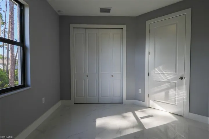 Unfurnished bedroom with light marble finish floors and a closet