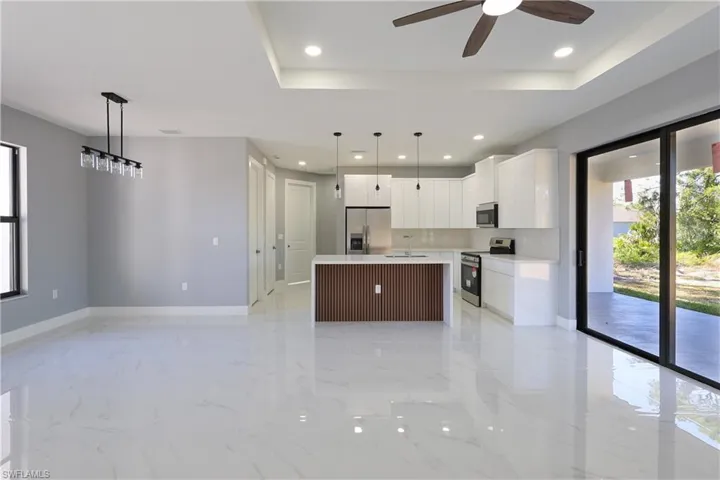 Kitchen featuring plenty of natural light, a center island with sink, decorative light fixtures, white cabinetry, and recessed lighting