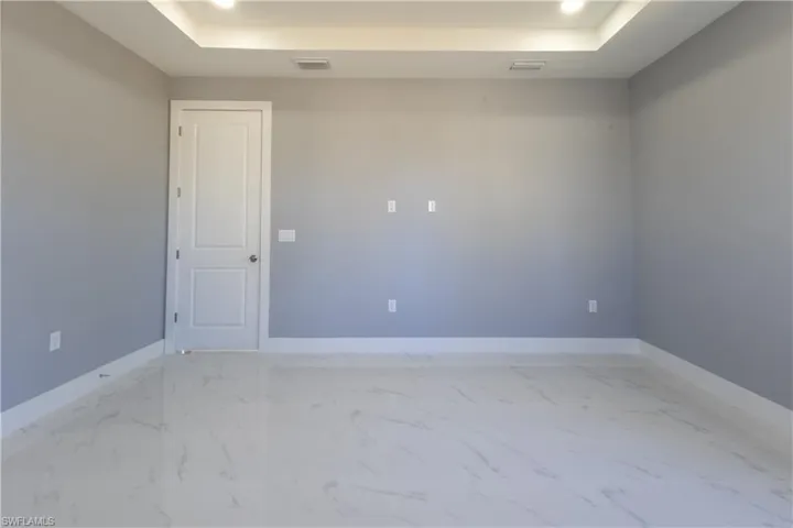 Spare room with light marble finish floors, recessed lighting, and a raised ceiling