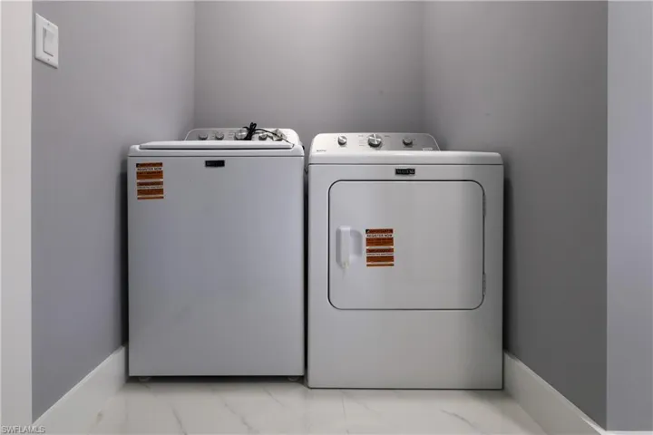 Laundry area featuring light marble finish floors and washing machine and dryer