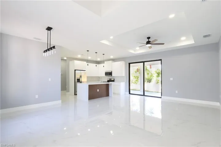 Kitchen featuring open floor plan, hanging light fixtures, recessed lighting, light marble finish flooring, and white cabinets