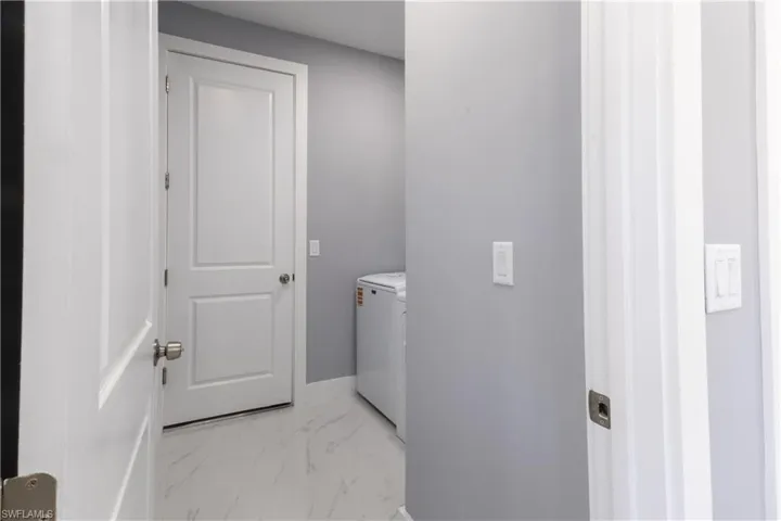 Laundry area with light marble finish floors and baseboards