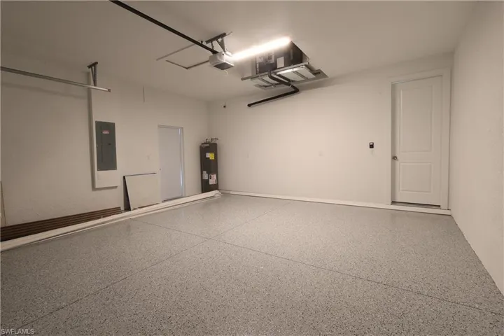Garage with electric panel, water heater, and a garage door opener