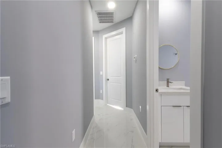 Hallway featuring light marble finish flooring and baseboards