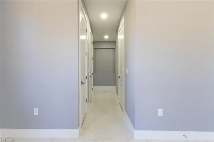 Corridor with light marble finish flooring and recessed lighting