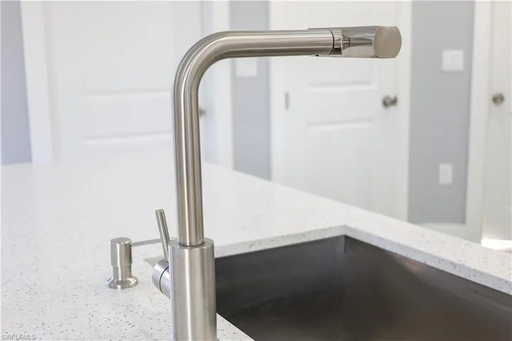 Kitchen view of a sink and light stone countertops