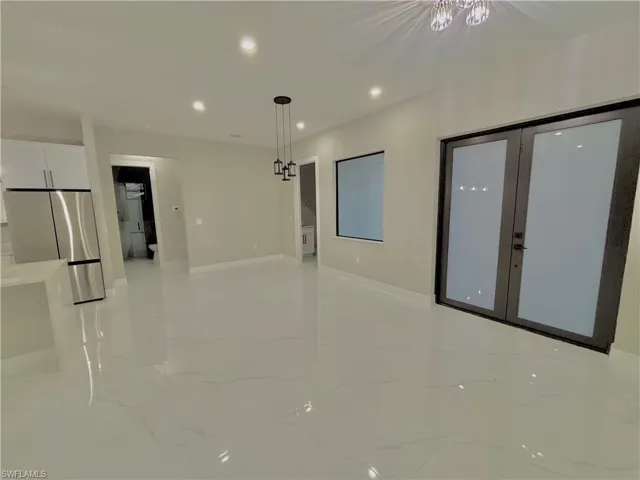 Empty room featuring recessed lighting, light marble finish flooring, and french doors