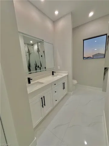 Full bathroom featuring double vanity, a marble finish shower, and recessed lighting