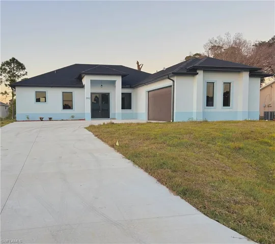 Prairie-style house featuring a front lawn, stucco siding, driveway, and an attached garage