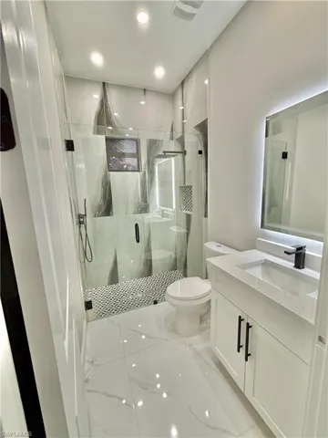 Full bathroom with vanity, a marble finish shower, and light marble finish flooring