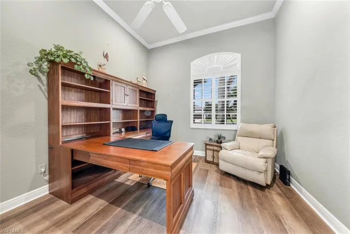 Office space with ceiling fan, wood-type flooring, and ornamental molding