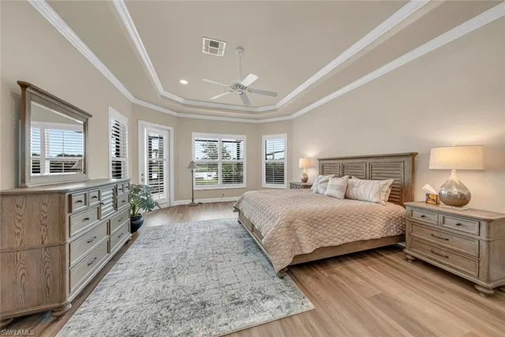 Bedroom with light hardwood / wood-style flooring, ceiling fan, a raised ceiling, and crown molding