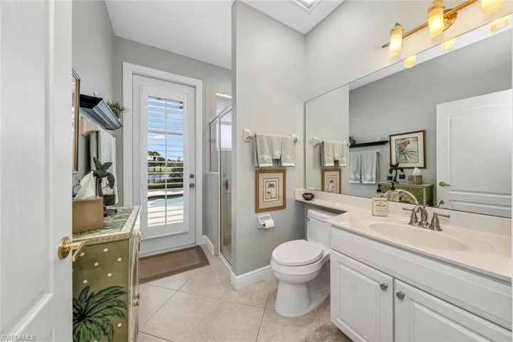 Bathroom featuring a shower with shower door, tile patterned floors, toilet, and vanity