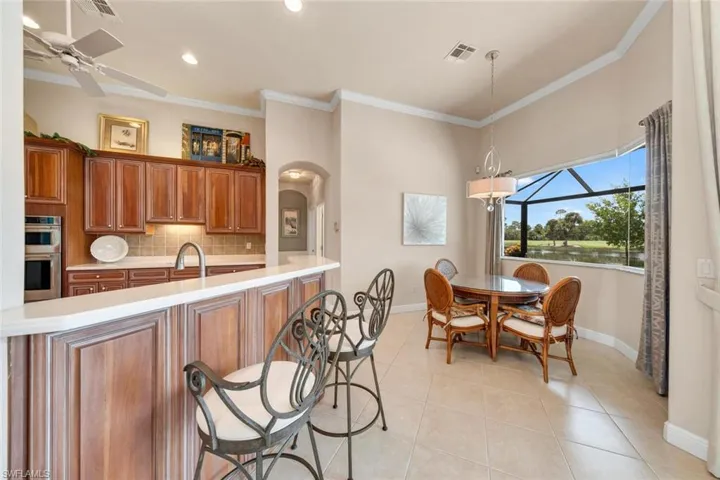 Kitchen with crown molding, light tile patterned floors, backsplash, ceiling fan, and double oven