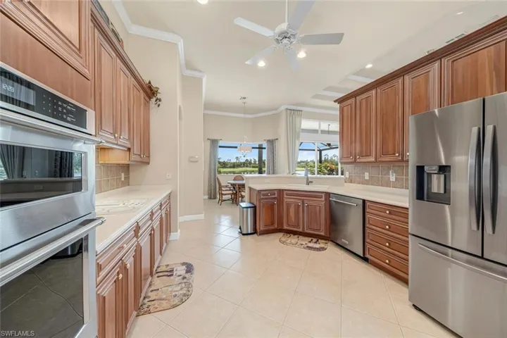 Kitchen with ornamental molding, light tile patterned floors, tasteful backsplash, and stainless steel appliances