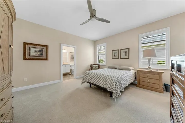 Bedroom with light carpet, ceiling fan, and connected bathroom
