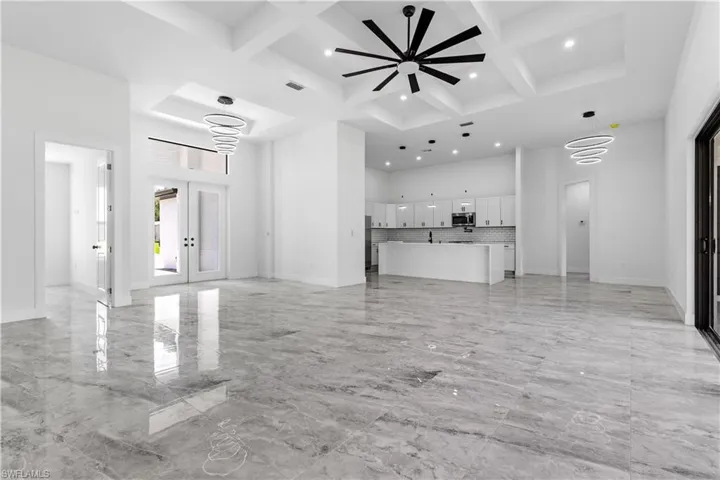 Unfurnished living room with beam ceiling, light tile patterned flooring, and coffered ceiling