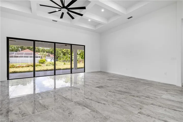 Unfurnished room featuring beamed ceiling, light tile patterned flooring, coffered ceiling, and ceiling fan
