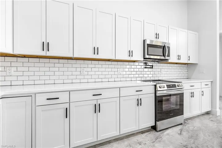 Kitchen featuring white cabinets, stainless steel appliances, backsplash, and light tile patterned floors