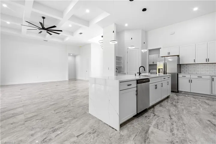 Kitchen featuring ceiling fan, pendant lighting, coffered ceiling, appliances with stainless steel finishes, and backsplash