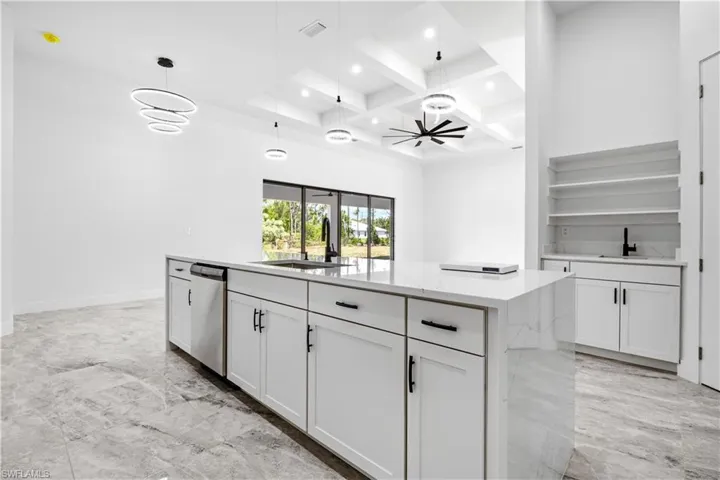 Kitchen featuring white cabinets, a center island, hanging light fixtures, and dishwasher