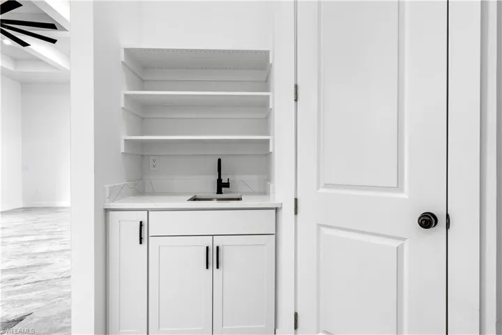 Bar featuring sink, hardwood / wood-style floors, and white cabinetry