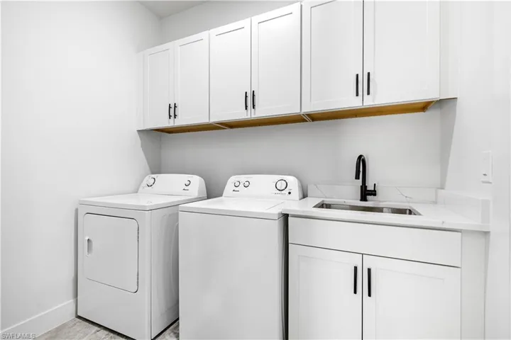 Washroom featuring washing machine and clothes dryer, sink, and cabinets