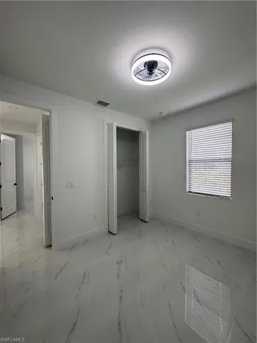 Firth unfurnished bedroom featuring light marble finish floors and a closet