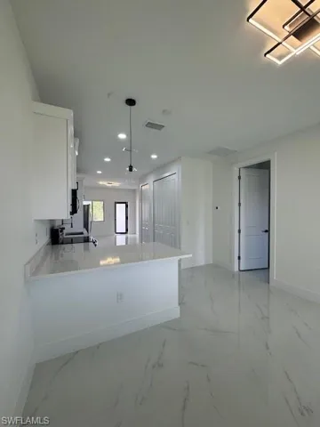 Kitchen with white cabinetry, light marble finish floors, a peninsula, recessed lighting, and pendant lighting