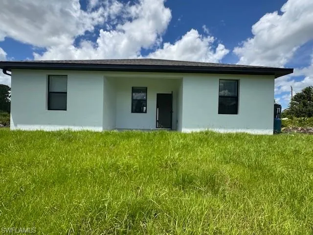 Rear view of house featuring stucco siding and a lawn