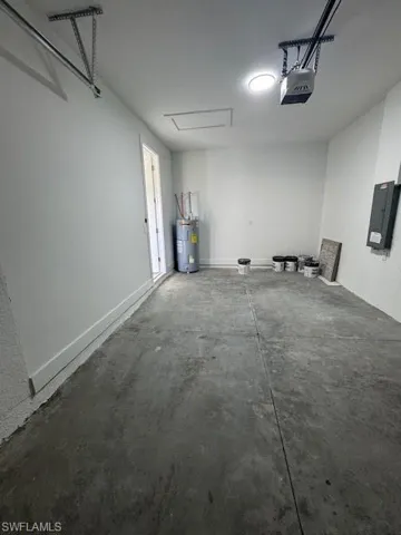 Garage featuring electric panel, a garage door opener, and water heater