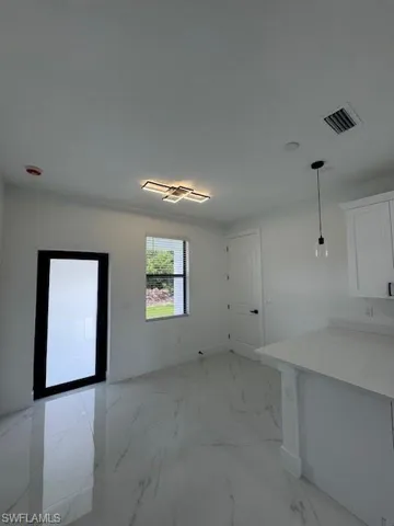 Unfurnished dining area with light marble finish floors and baseboards