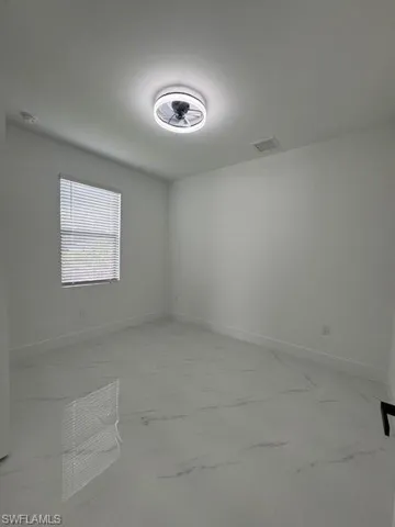 Spare room featuring light marble finish flooring and baseboards