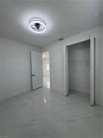 Second unfurnished bedroom featuring light marble finish flooring and a closet