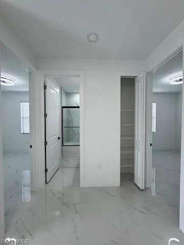 views from hallway of two bed, bath & aux. closet,  featuring light marble finish floors and connected bathroom