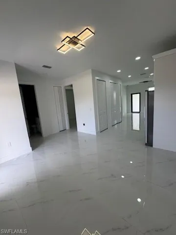 Empty room featuring light marble finish floors and recessed lighting