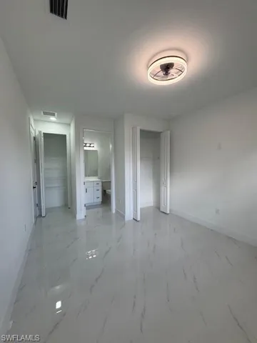 Master Primary unfurnished bedroom with a closet, light marble finish flooring, and ensuite bathroom