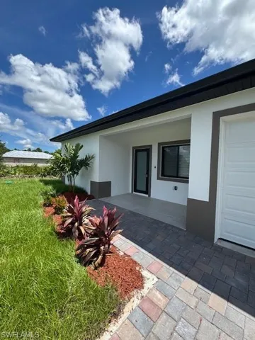 Entrance to property featuring stucco siding, a garage, and a patio