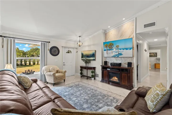 Tiled living room featuring crown molding and a large fireplace