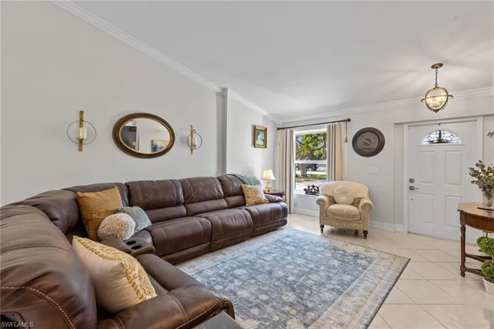 Tiled living room featuring crown molding and lofted ceiling