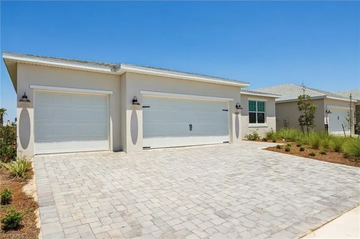 Ranch-style house featuring stucco siding, decorative driveway, and an attached garage