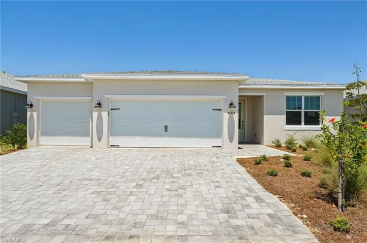 View of front facade with a garage, decorative driveway, and stucco siding