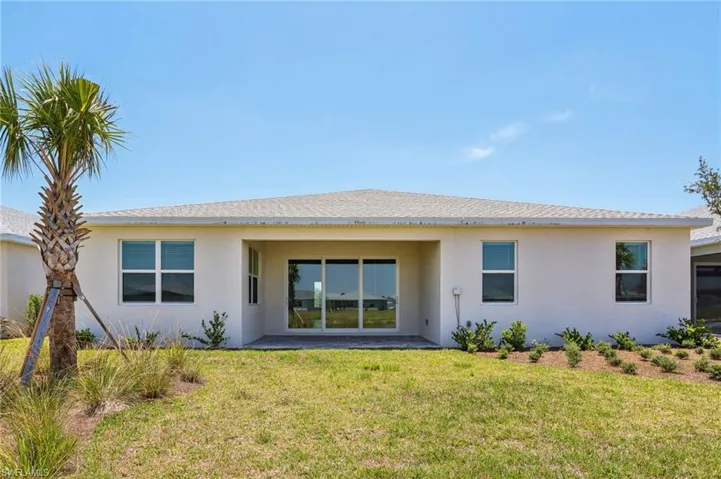 Rear view of property featuring stucco siding and a yard