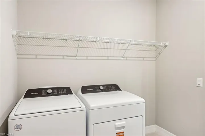 Washroom featuring independent washer and dryer and baseboards