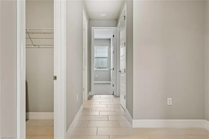 Hall with light tile patterned floors and baseboards