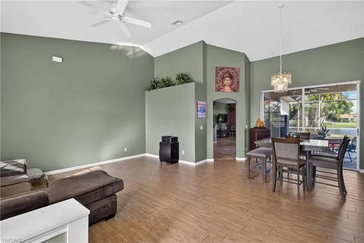 Vaulted ceilings with recessed lighting, wood-finish flooring, built-in decorative display ledge, and sliding glass doors