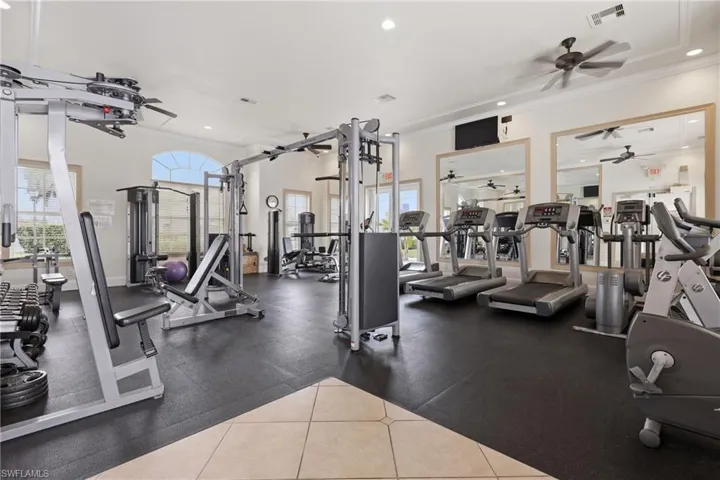 Spacious fitness center featuring  with ceiling fans, recessed lighting, and large mirrors