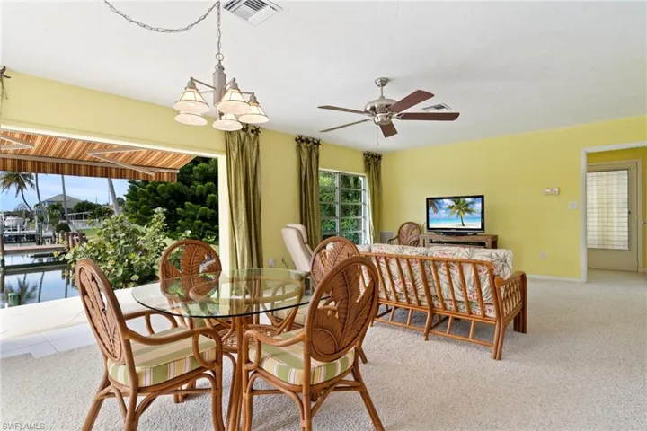 Carpeted dining room with ceiling fan and hanging lights