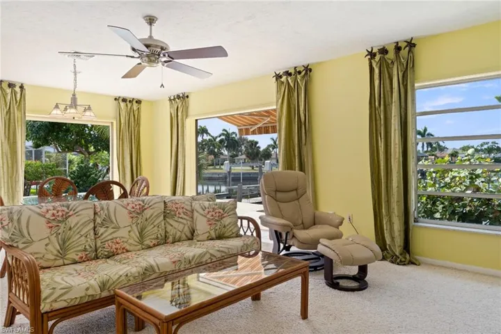 Carpeted living area with a ceiling fan and a water view