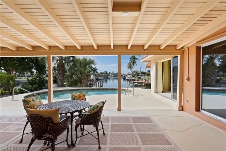 View of patio with an outdoor pool, outdoor dining area, and a water view